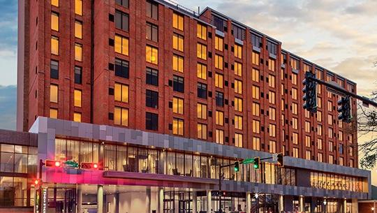 Modern red brick building with lots of windows against a gold and blue sky